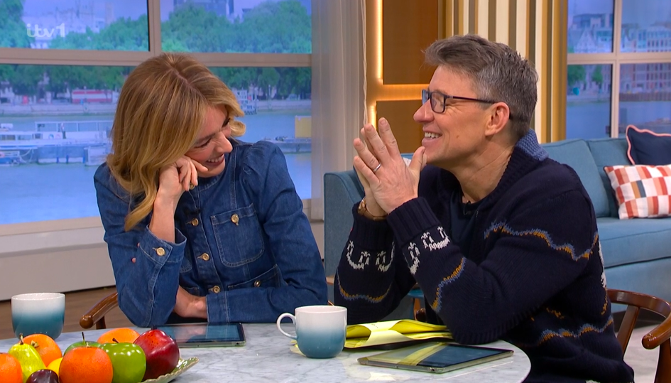 Screenshot of two people laughing and talking on a television show.