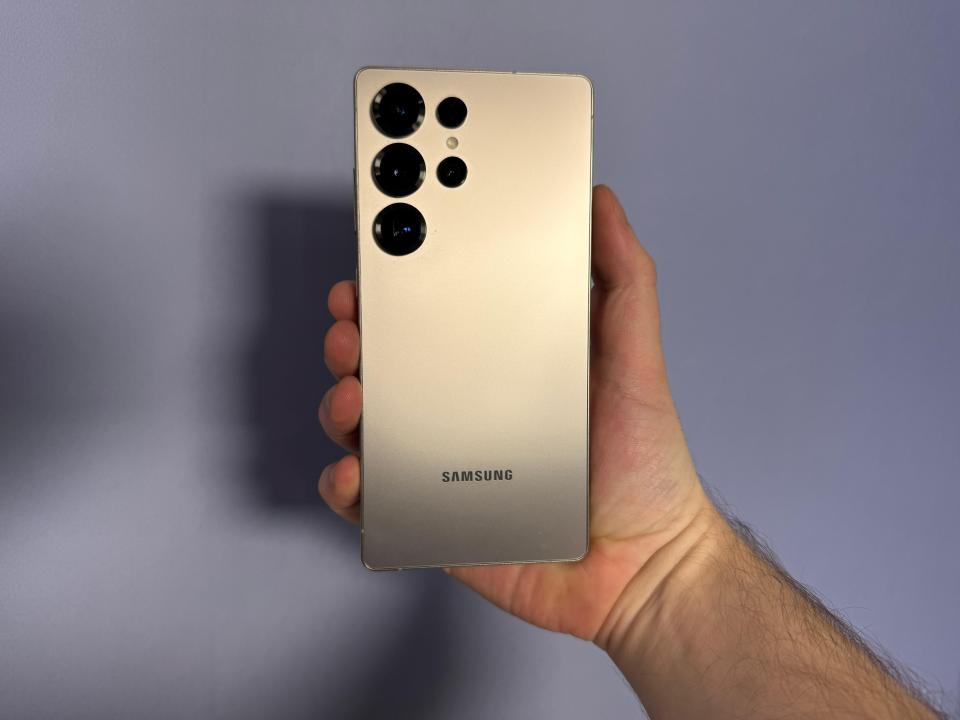 A hand holding a gold Samsung phone.
