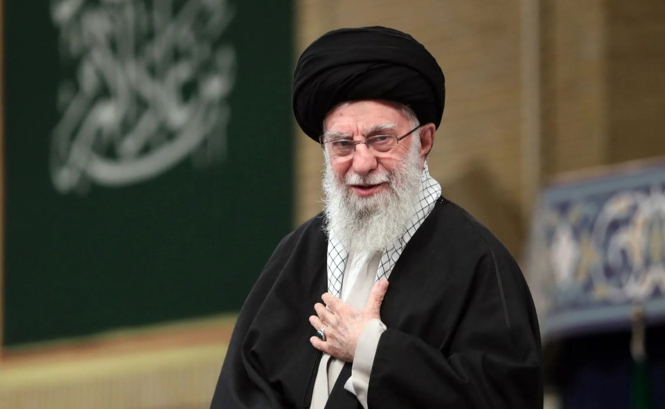 a man with a beard and glasses holds his hand to his chest