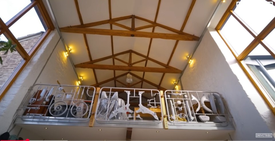 Interior view of a barn with a mezzanine level; the railing is decorated with car parts.