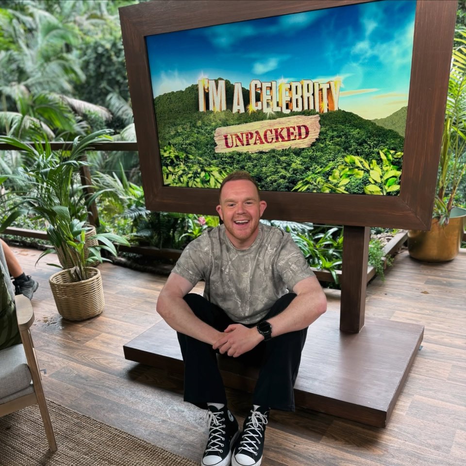Colson Smith sitting in front of an "I'm a Celebrity... Unpacked" sign.
