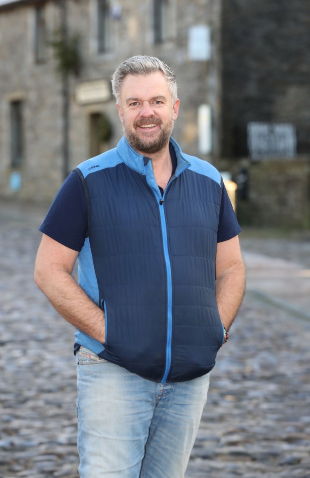Man in blue vest standing in a village.
