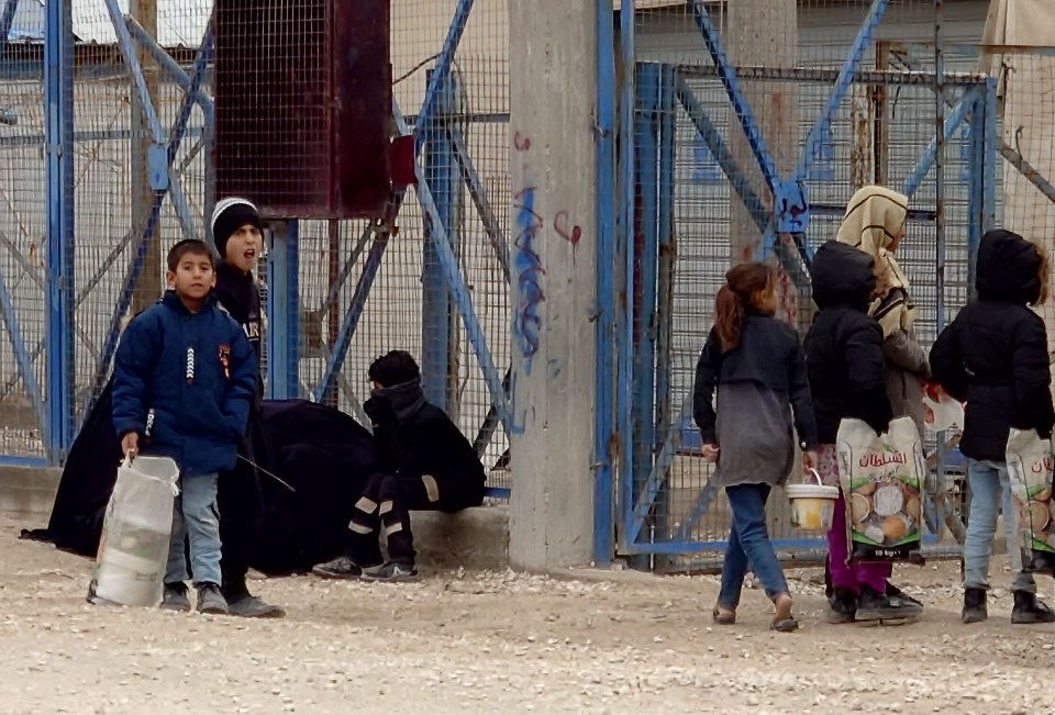 Children near a fence carrying bags of food.