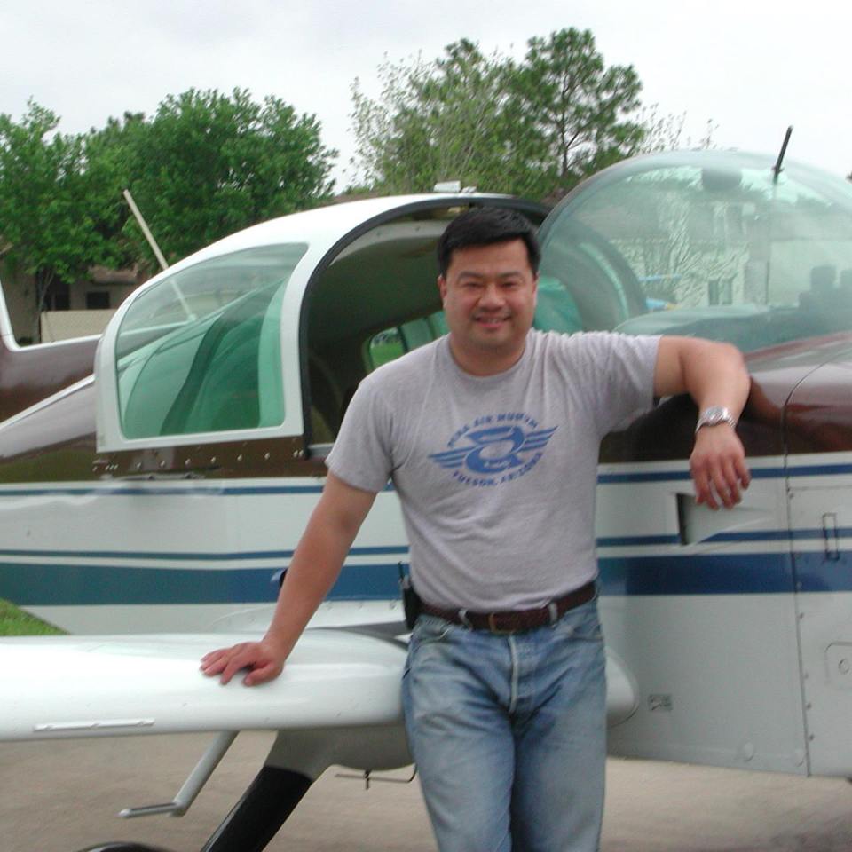 Dr. Leroy Chiao leaning on a small airplane.