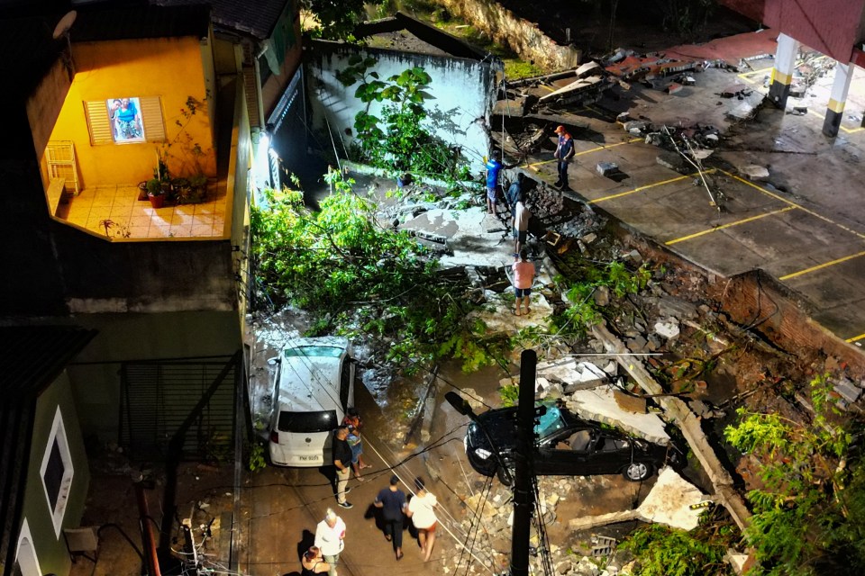 Drone view of flood damage: people inspecting houses and cars.