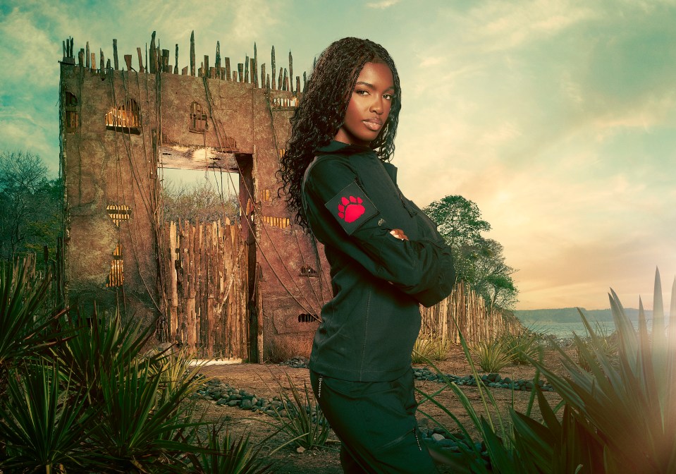 Leomie Anderson, contestant on Celebrity Bear Hunt, stands before a dilapidated structure.