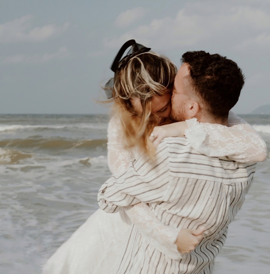 A man embraces a woman on a beach.