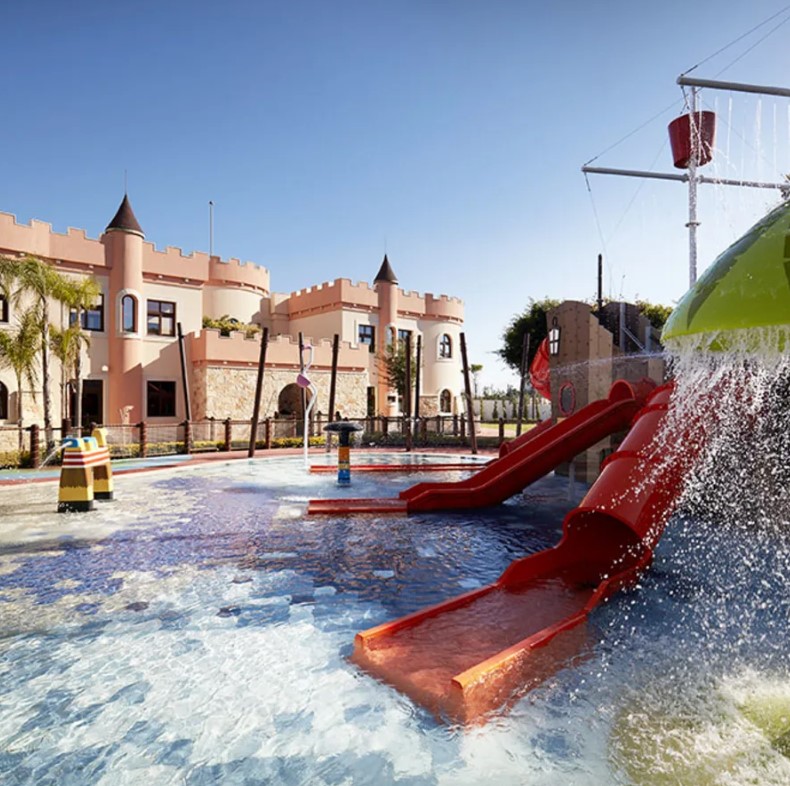 Kids' water play area with slides and castle-themed building.