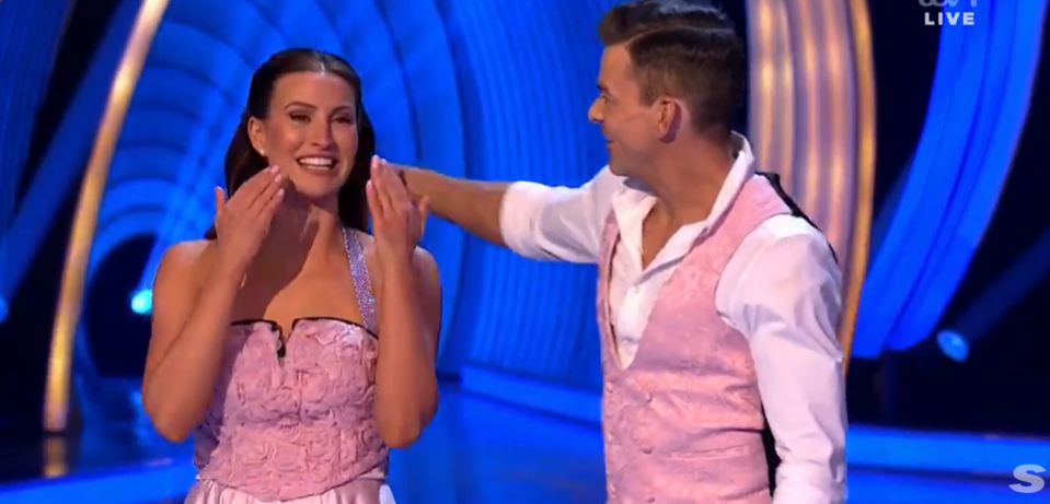 A woman in a pink dress is touched on the face by a man in a pink vest.