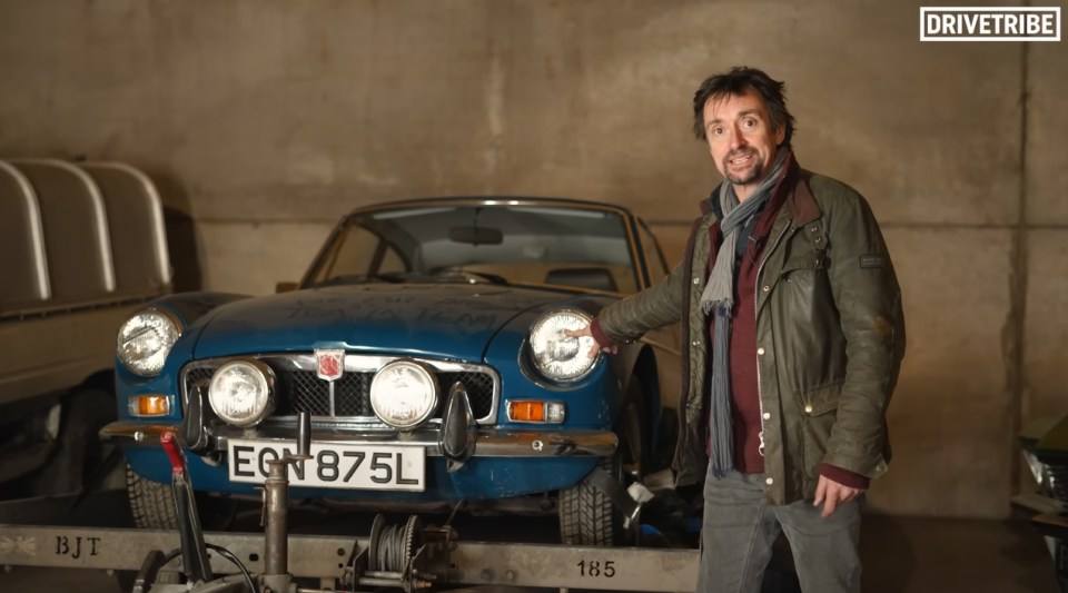 Richard Hammond standing next to a blue classic car in a garage.