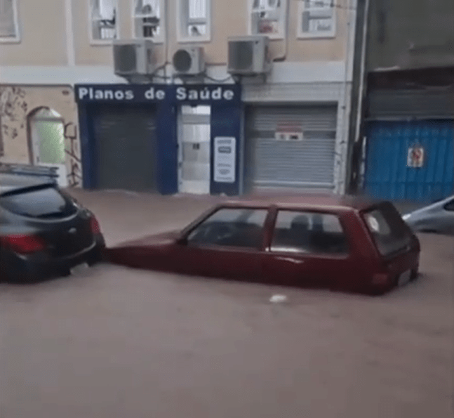 Two cars submerged in floodwater on a city street.