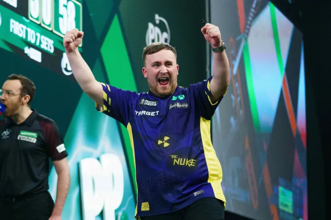 A victorious darts player celebrates with arms raised.