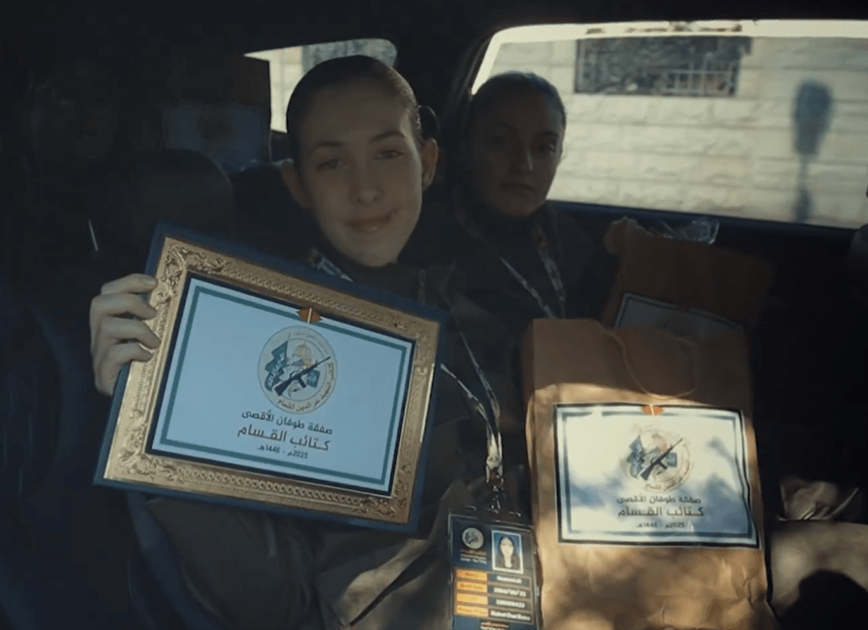 Two women in a car holding certificates from the Qassam Brigades.
