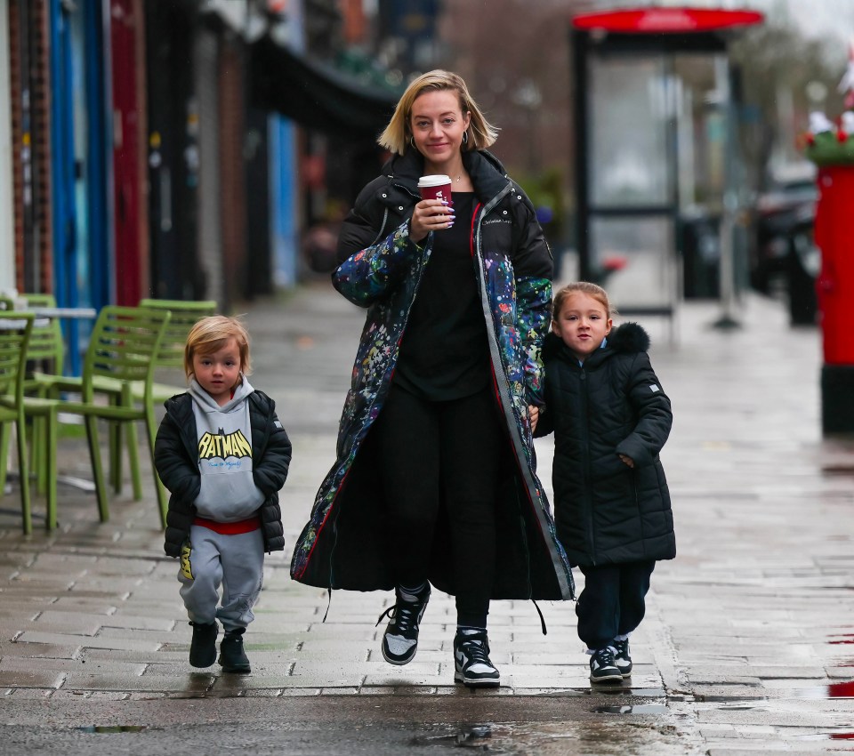 Kelsey Parker walking with her two children while holding a coffee cup.
