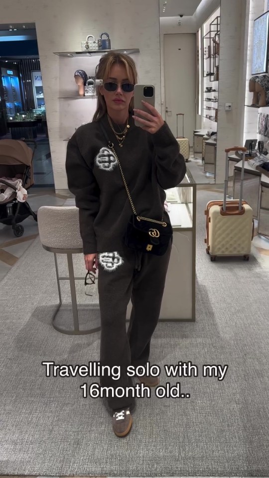 Woman in dark brown sweatsuit traveling solo with her 16-month-old child.