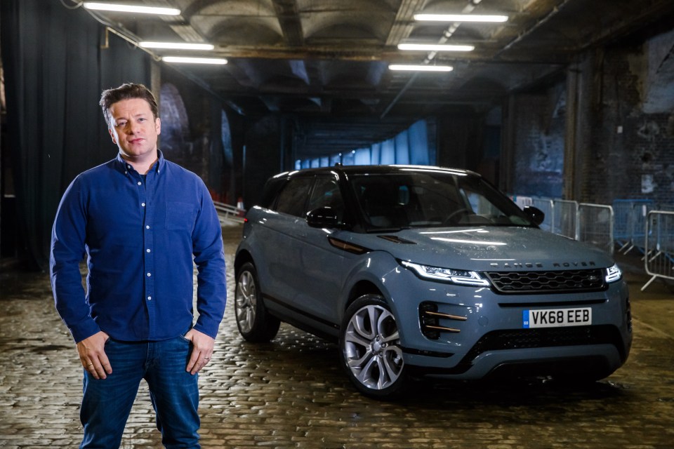 Jamie Oliver standing next to a Range Rover Evoque.