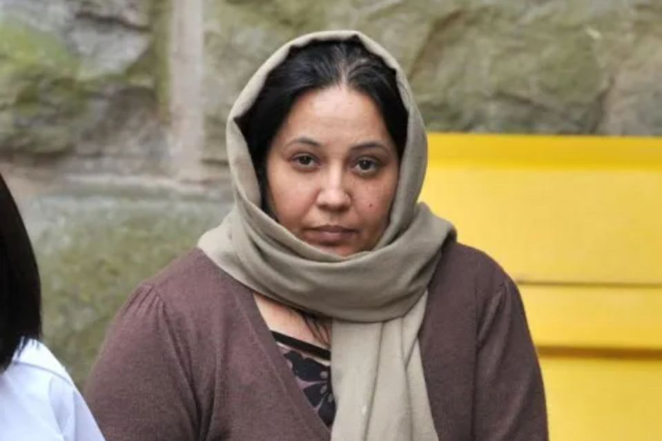 Woman wearing a brown sweater and tan scarf.