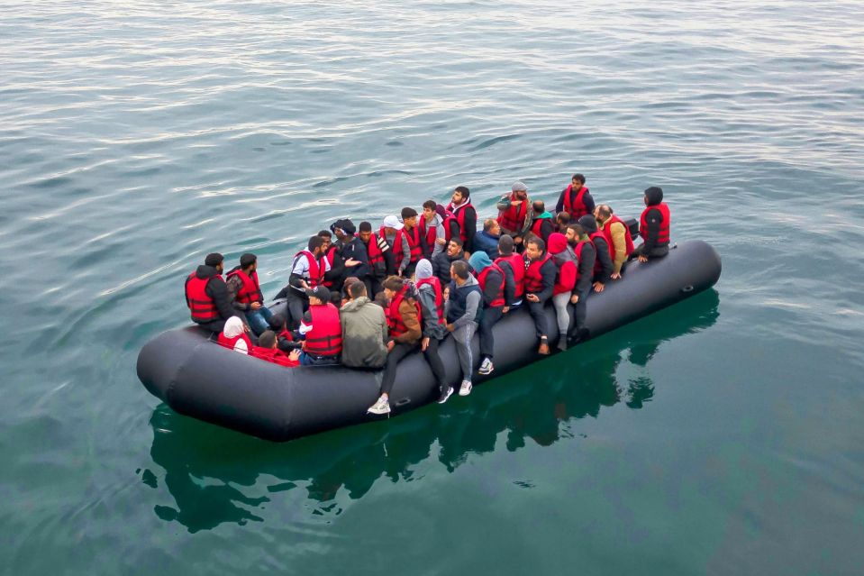 Many people in a crowded inflatable boat at sea.