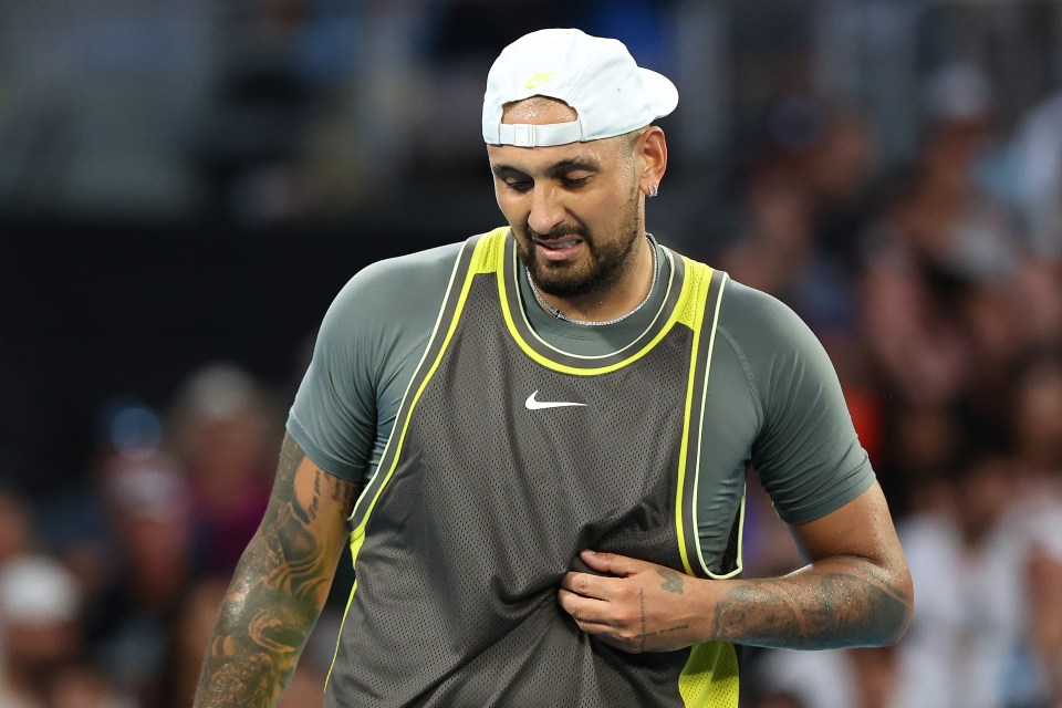 Nick Kyrgios of Australia holding his stomach during a tennis match.