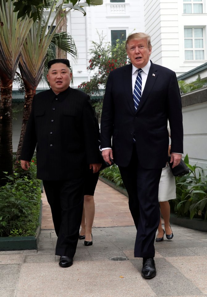 Kim Jong Un and Donald Trump walking in a garden.