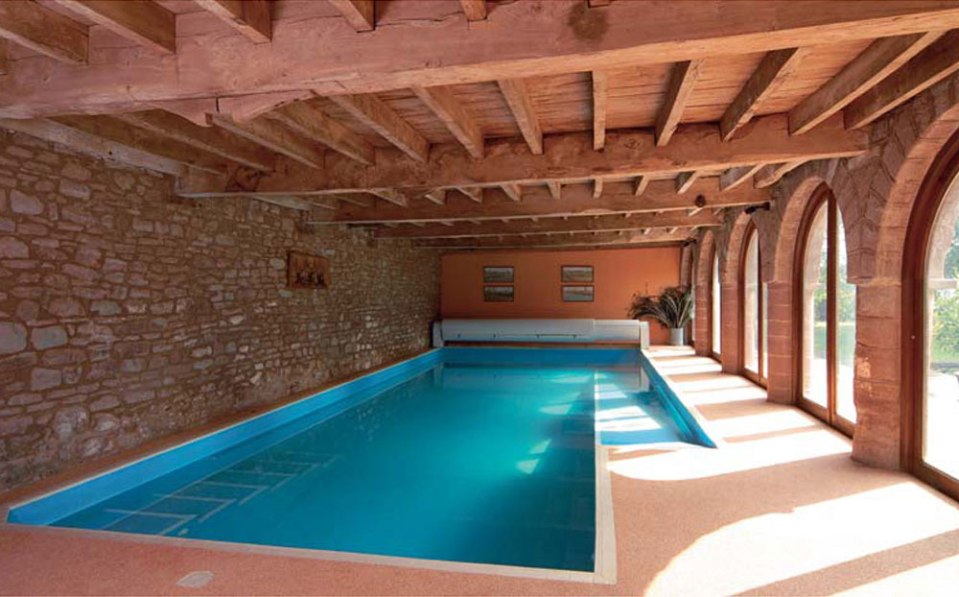 Indoor swimming pool in a stone building with wooden beams.