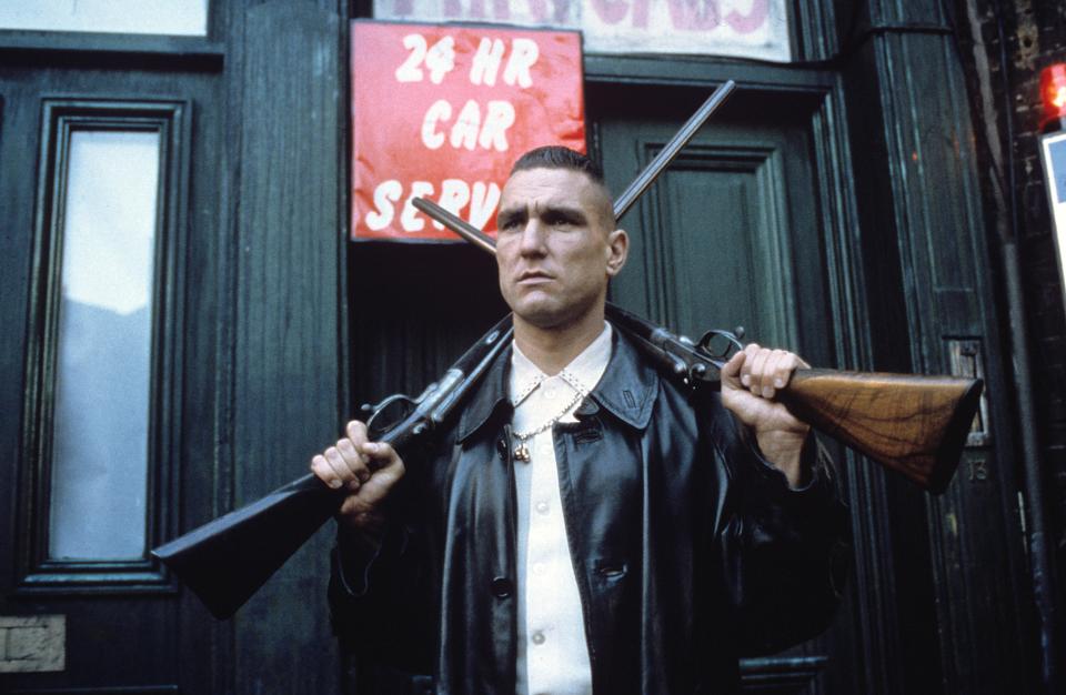 Film still of Vinnie Jones in *Lock, Stock and Two Smoking Barrels*, carrying two shotguns.