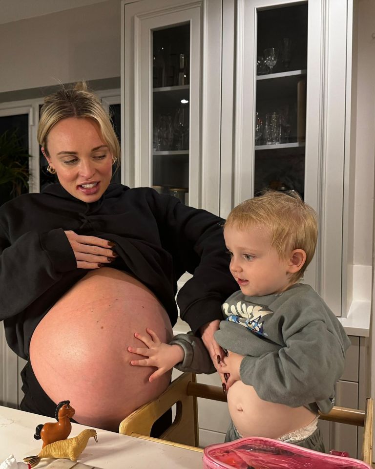 Pregnant woman and toddler touching her large baby bump.