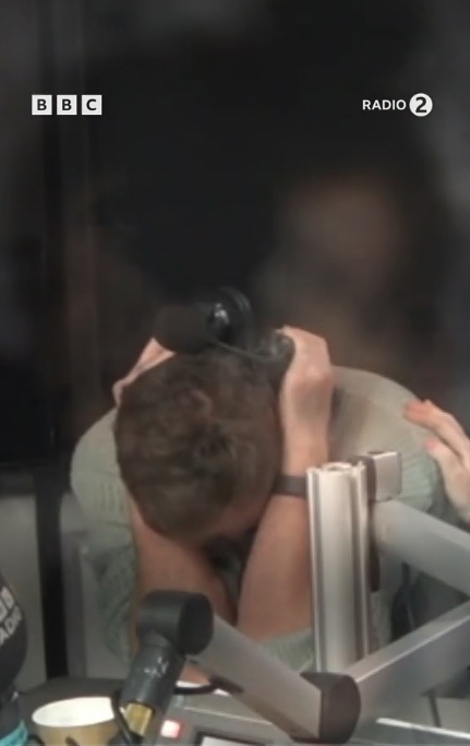 Scott Mills with his head in his hands in a BBC Radio 2 studio.