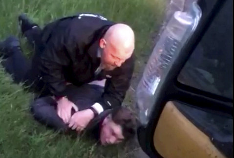Police officer arresting a man on the ground.