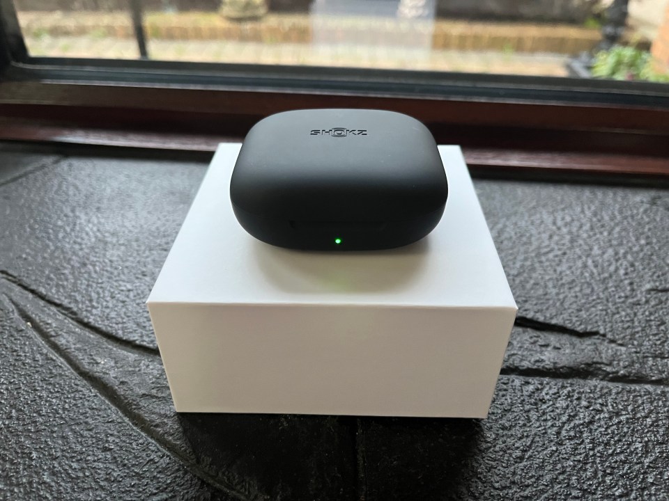Shokz OpenFit Air charging case with green light.