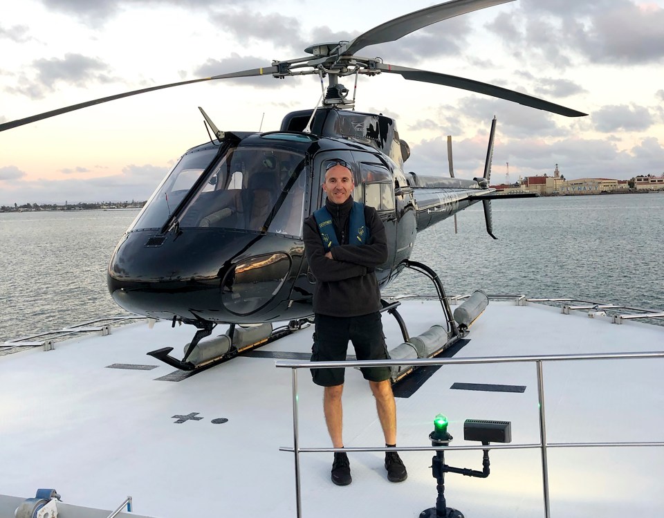 Helicopter pilot Ara Zobayan standing in front of a helicopter.