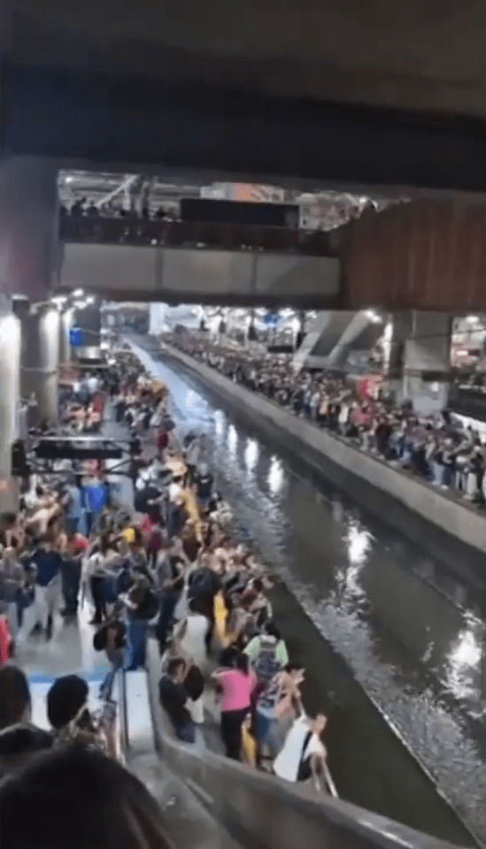 Crowds gather along a flooded canal.