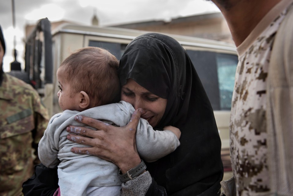 A crying woman holds a baby close.