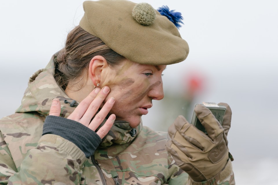 A British soldier applying camouflage paint to her face.