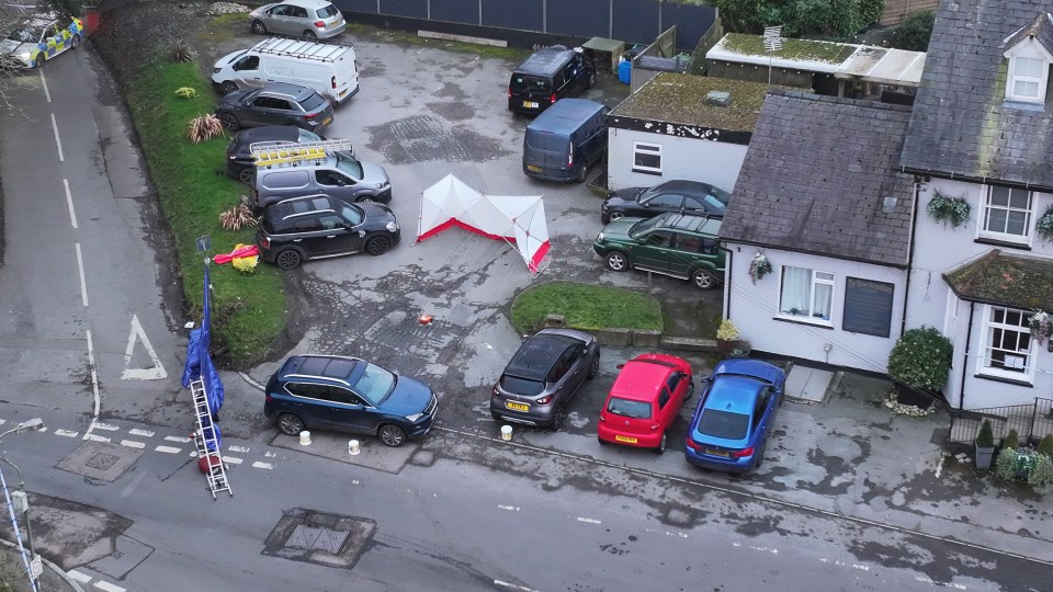 Aerial view of a crime scene with a forensics tent and police vehicles.