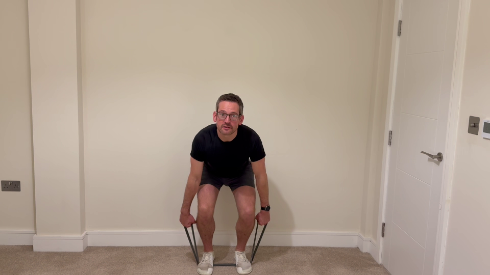 Man doing squats with resistance bands.