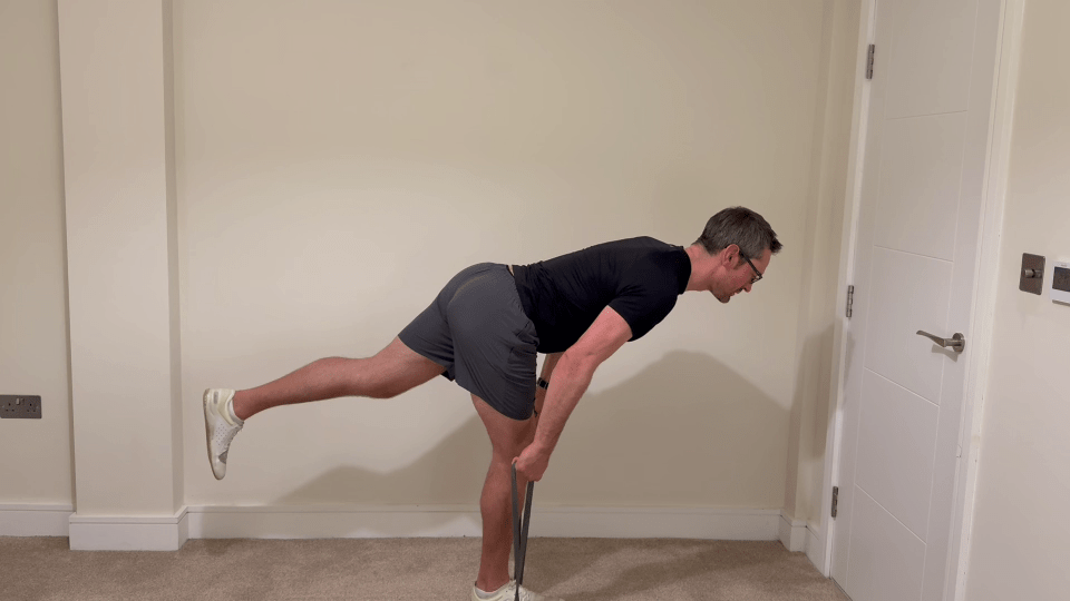 Man performing a single-leg deadlift with a resistance band.