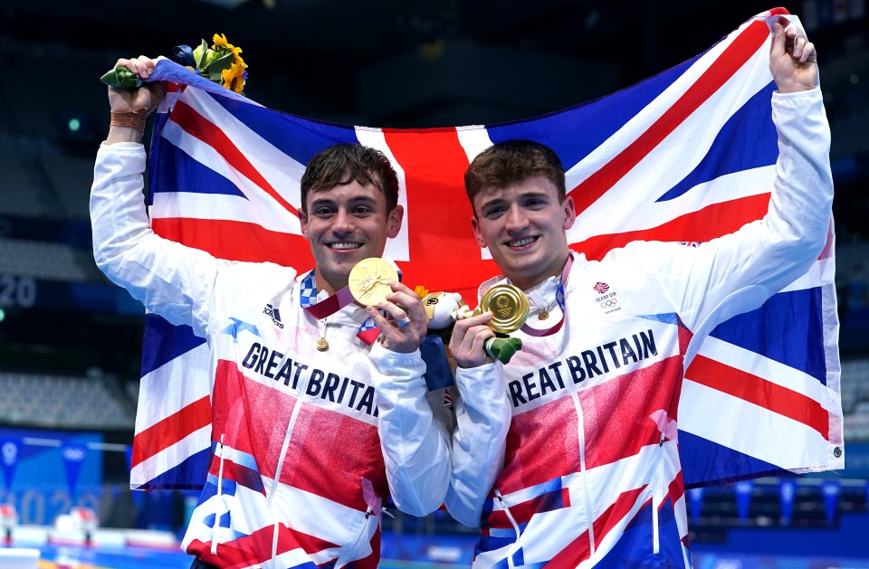 Two British Olympic divers holding gold medals and a Union Jack flag.