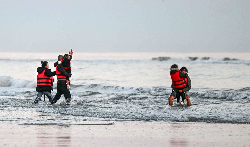 Migrant families arriving on a beach after a sea crossing.