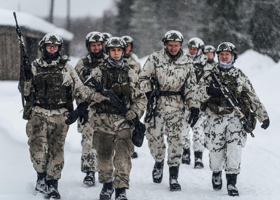 Finnish soldiers carrying rifles during winter training.