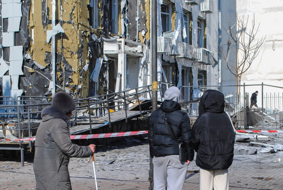 People stand near a damaged children's clinic in Odesa, Ukraine, after a drone strike.