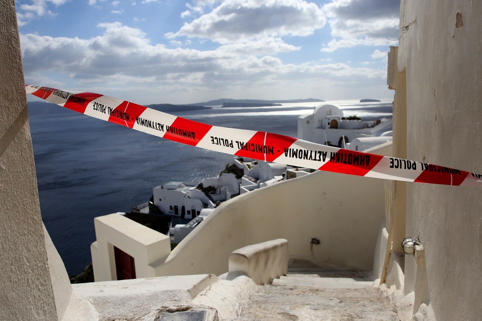 Red and white police tape across a street overlooking the sea in Santorini, Greece.