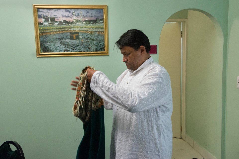 Man in white shirt preparing prayer rug.