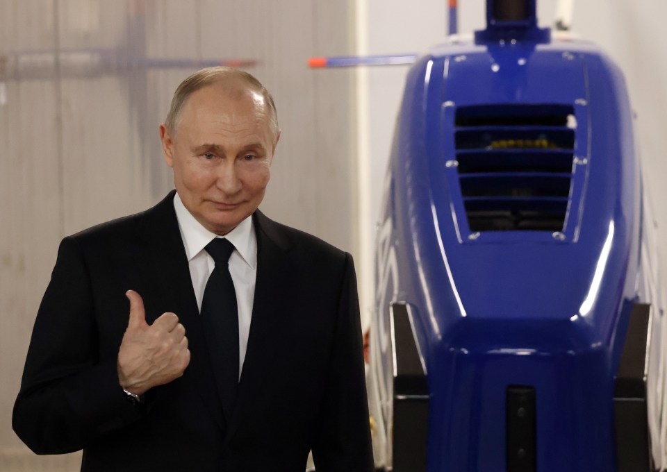 Vladimir Putin giving a thumbs-up at a military plant.