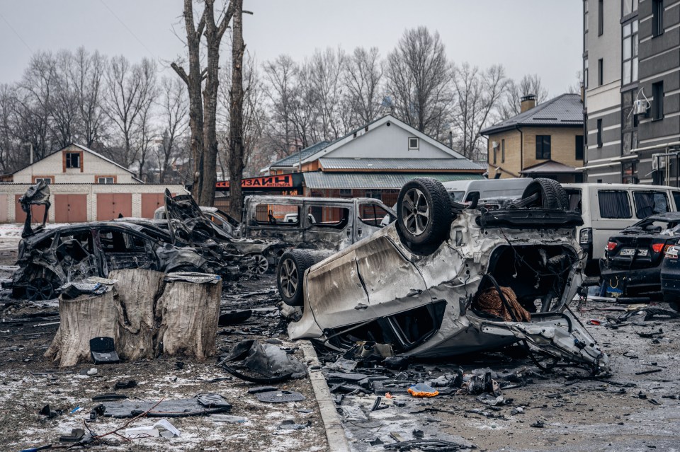 Burned and damaged cars in a parking lot after a drone attack.