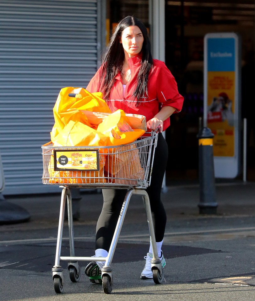 Woman pushing a shopping cart full of groceries.