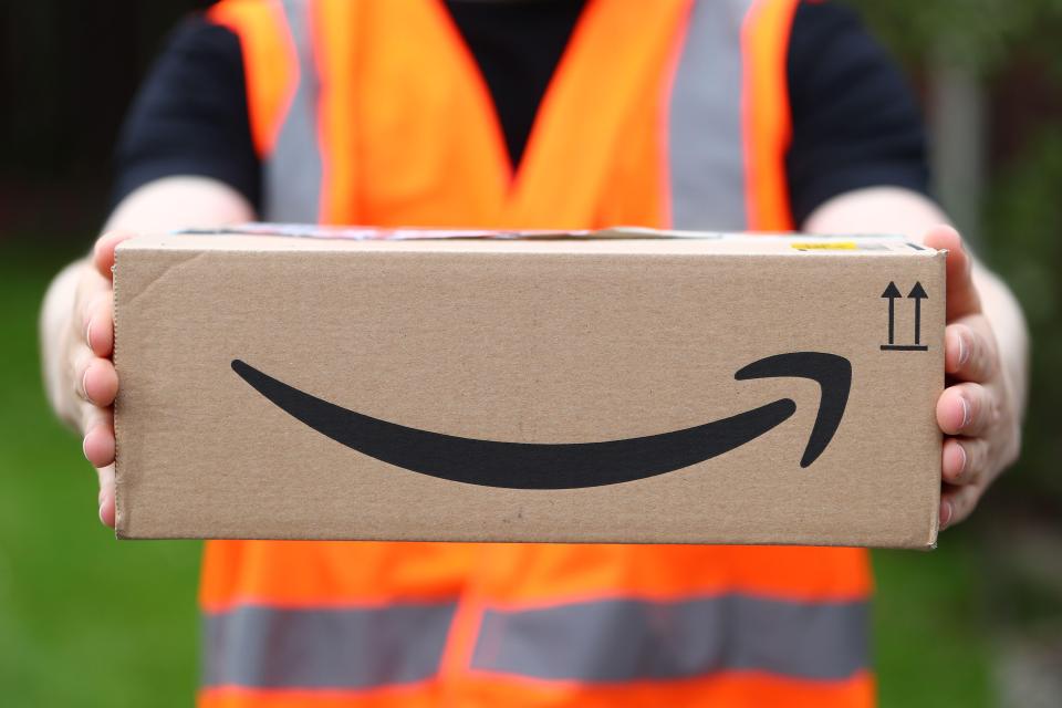 A delivery person holding an Amazon package.