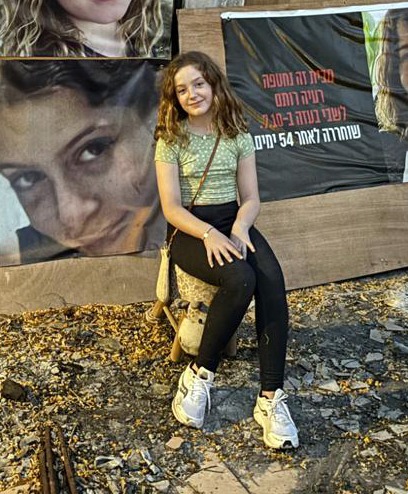 a girl sits in front of a wall with posters of a girl on it