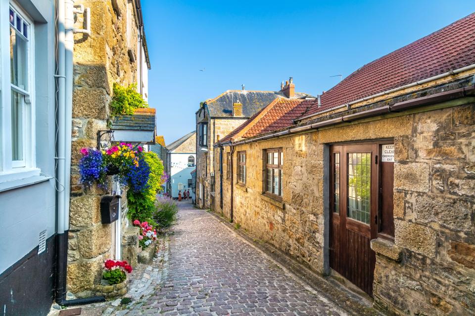 Cobblestone street in St Ives, Cornwall, lined with stone houses.