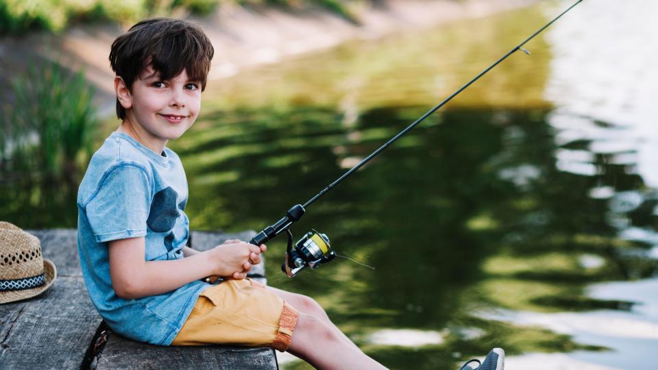 Happy boy fishing by a lake.